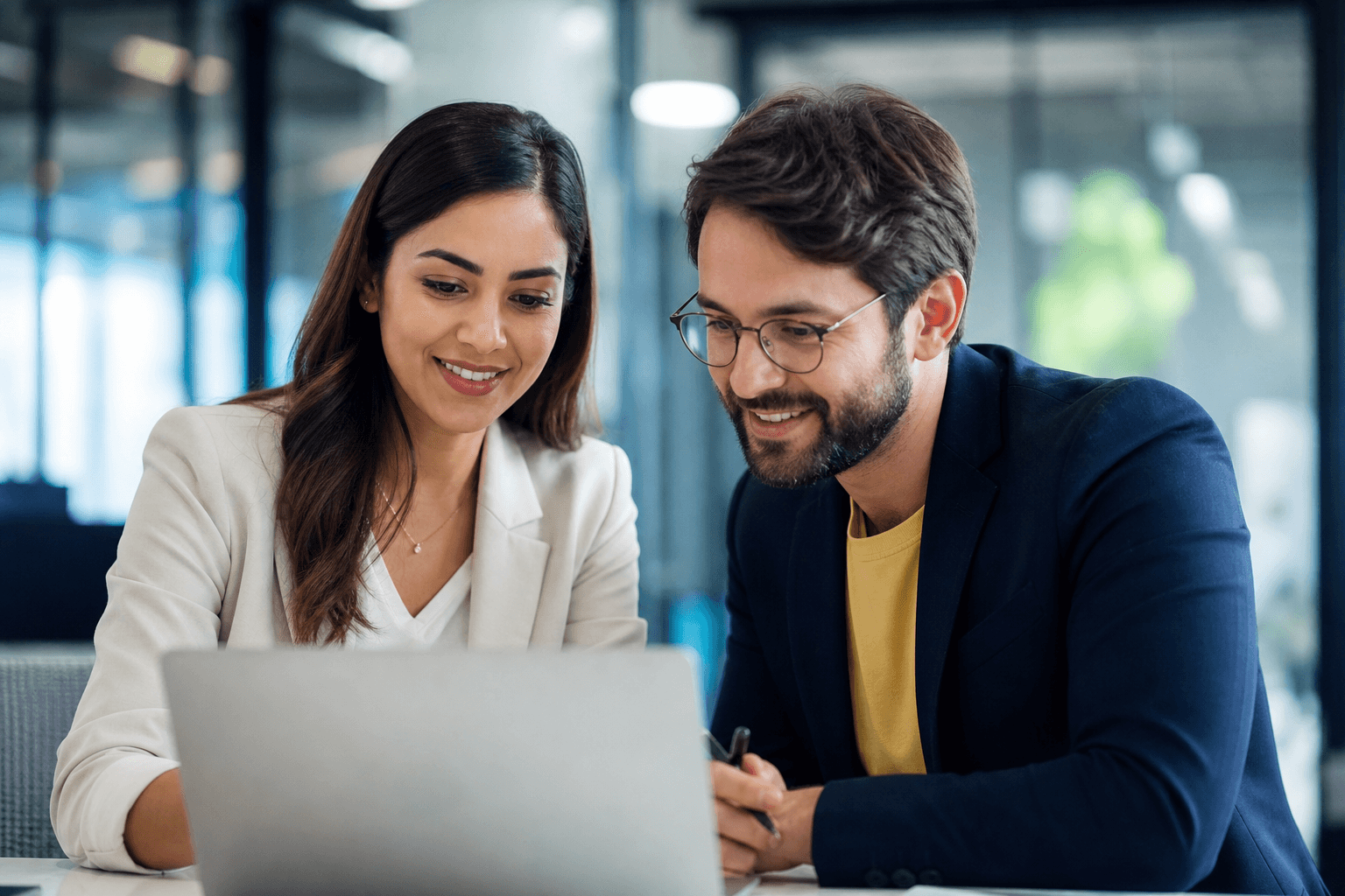 Professional man and woman collaborating on laptop in modern office